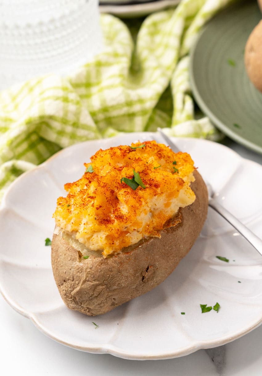 twice baked crab stuffed potato on a small white plate with a silver fork resting on the side