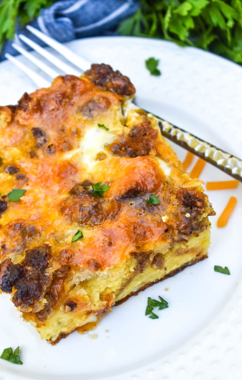 a slice of cheddar bay breakfast bake on a small white plate with a silver fork resting on the side