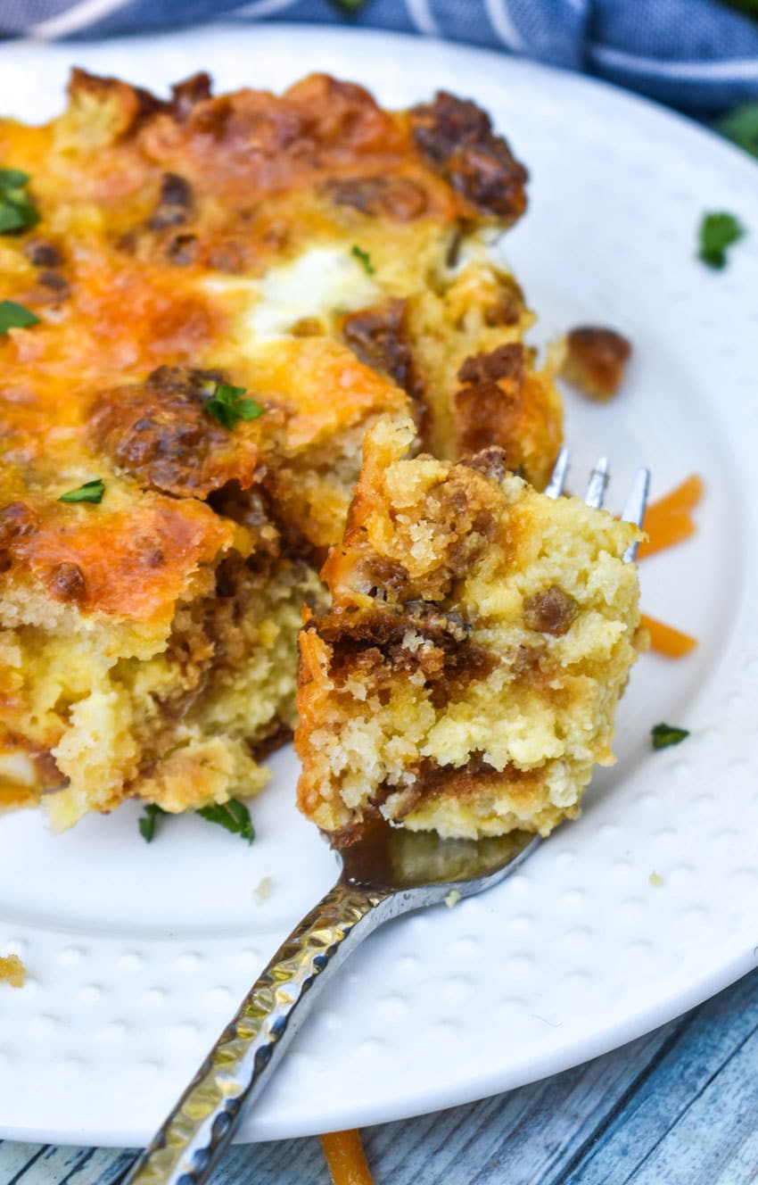 a piece of cheddar bay breakfast bake on a silver fork resting on the edge of a white plate