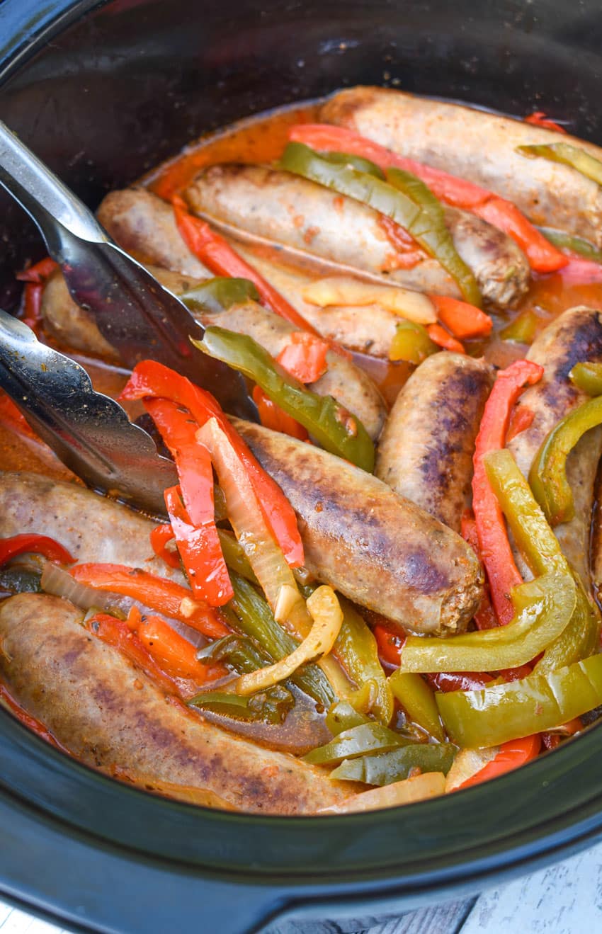 slow cooker sausage with peppers and onions in a black crock