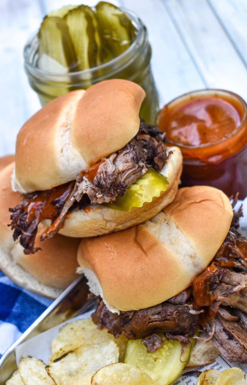 a stack of three smoked chuck roast sandwiches on a wooden table