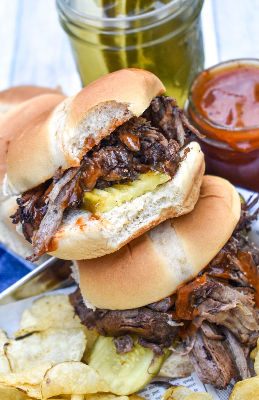 a stack of three smoked chuck roast sandwiches on a wooden table