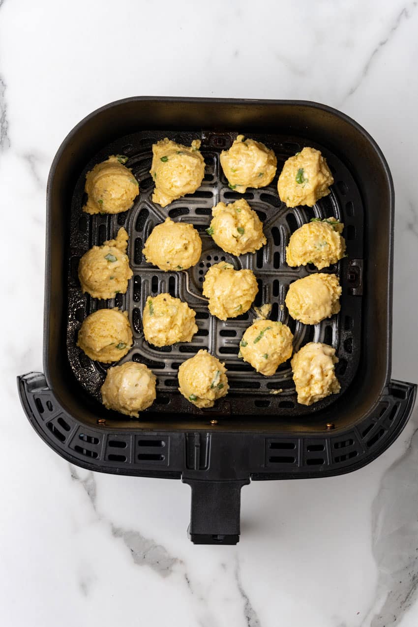 dollops of air fryer hush puppy dough in the basket of an air fryer