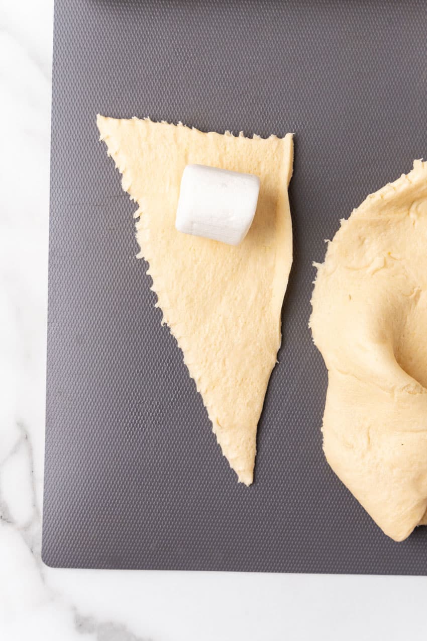 a large marshmallow on a crescent roll triangle on a gray cutting board