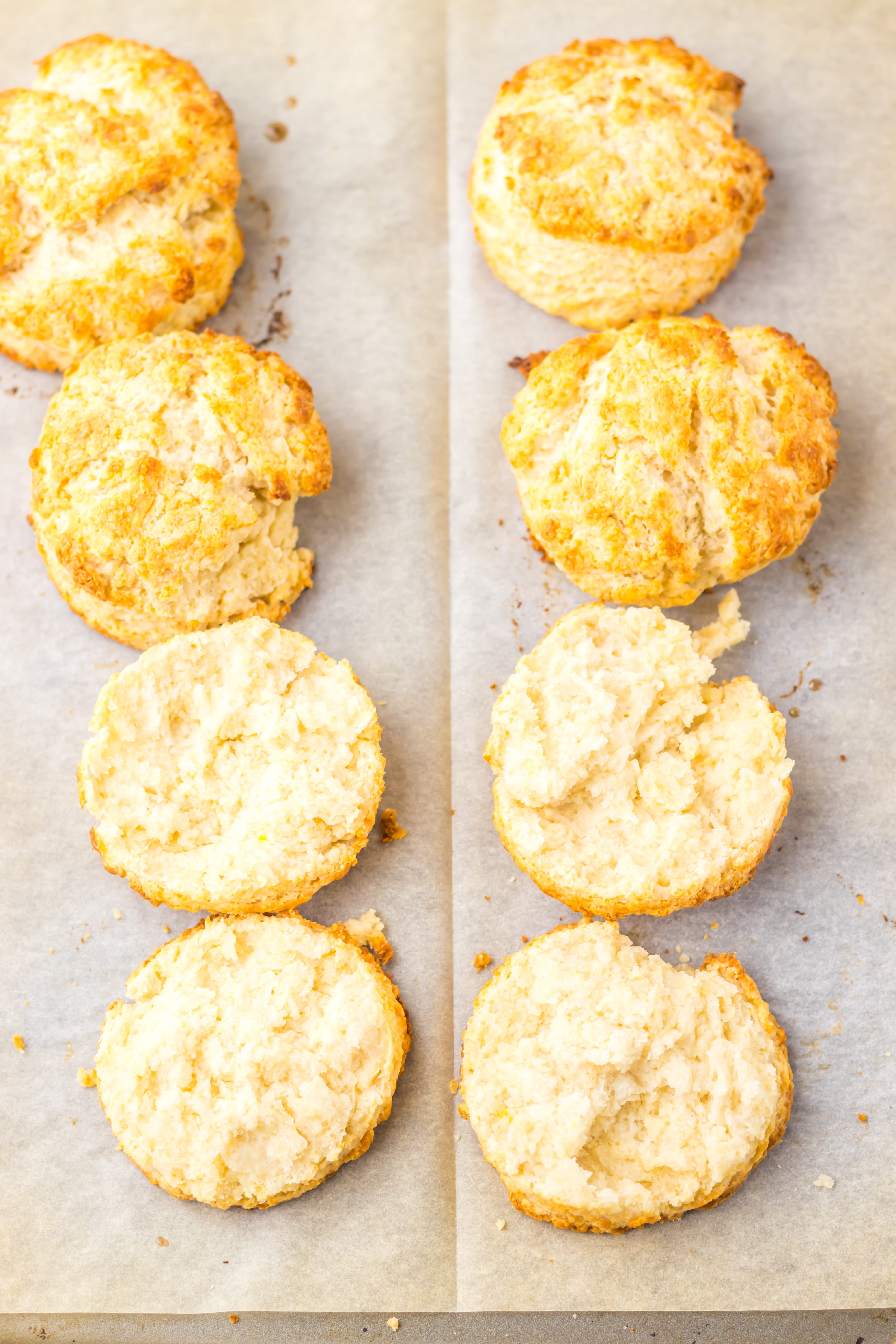 baked southern style biscuits cut in half and arranged in two rows on a parchment paper lined metal baking sheet