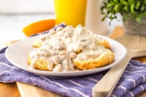 copycat cracker barrel sausage gravy over halved homemade biscuits on a white plate