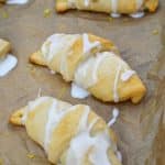 glazed lemon crescent rolls arranged in rows on a parchment paper lined baking sheet