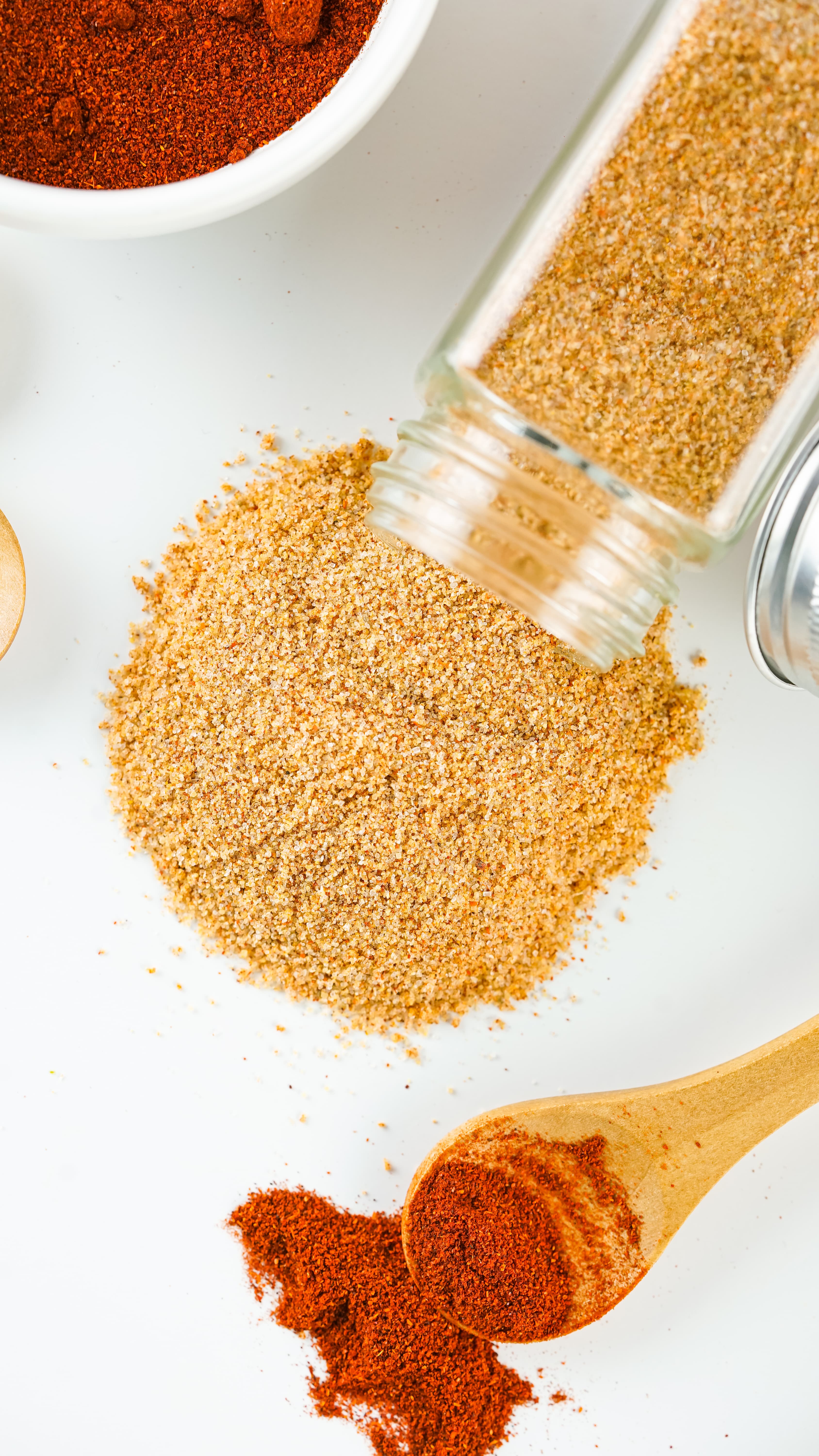 homemade seasoning salt spread out of it's small glass jar on a white counter