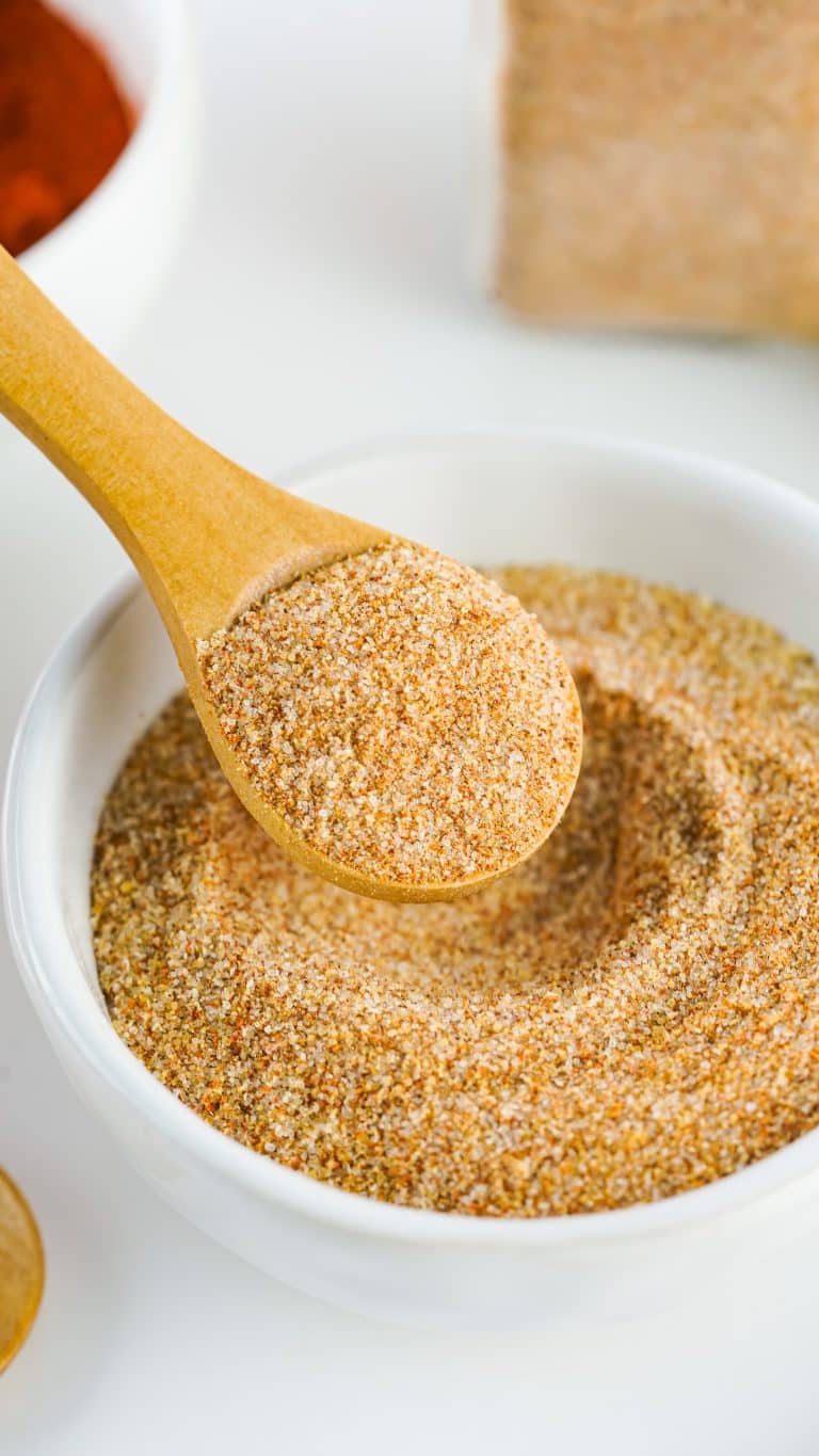 a wooden spoon scooping homemade seasoning salt out of a small white bowl