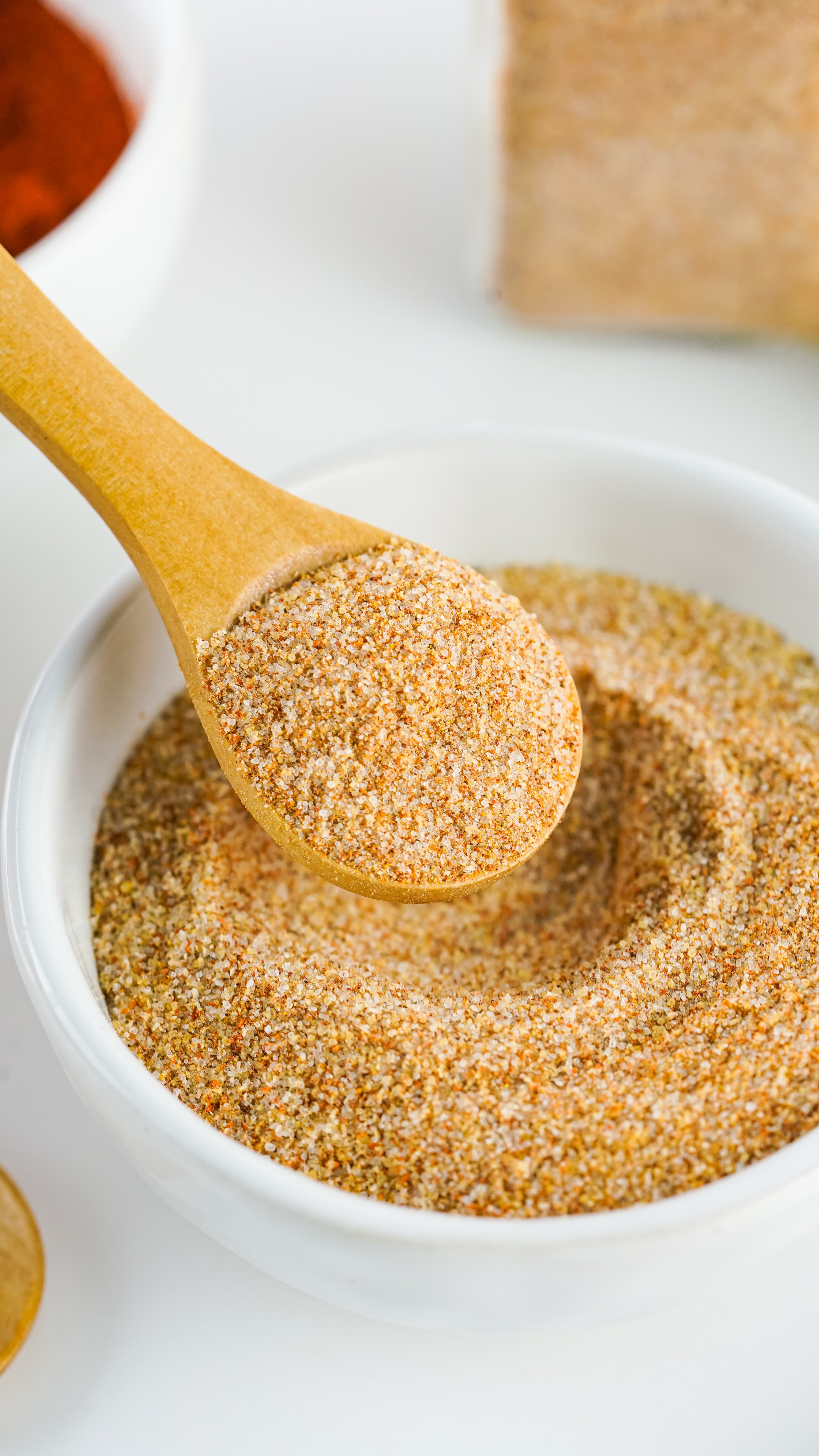 a wooden spoon scooping homemade seasoning salt out of a small white bowl