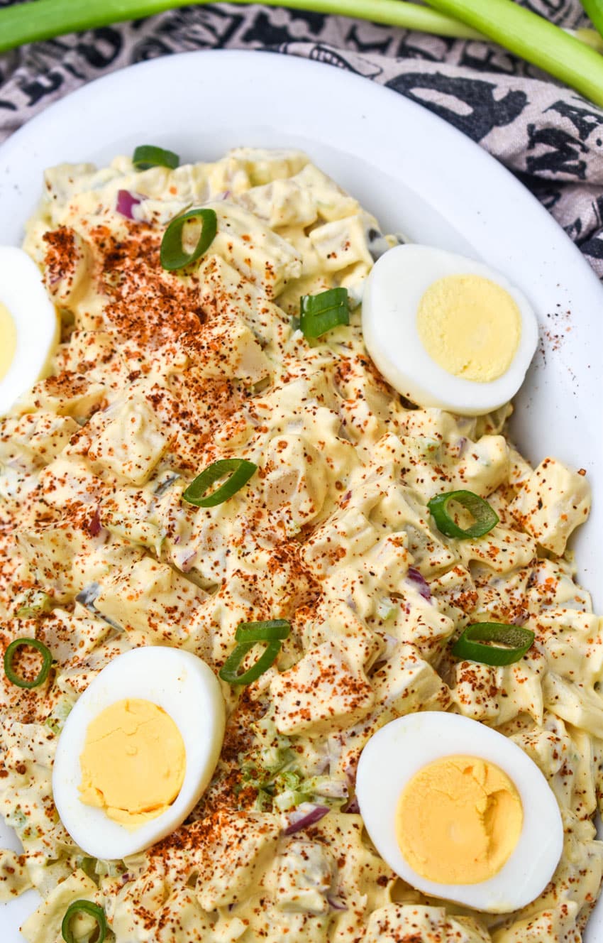 smoked potato salad topped with hard boiled egg halves in a white serving dish