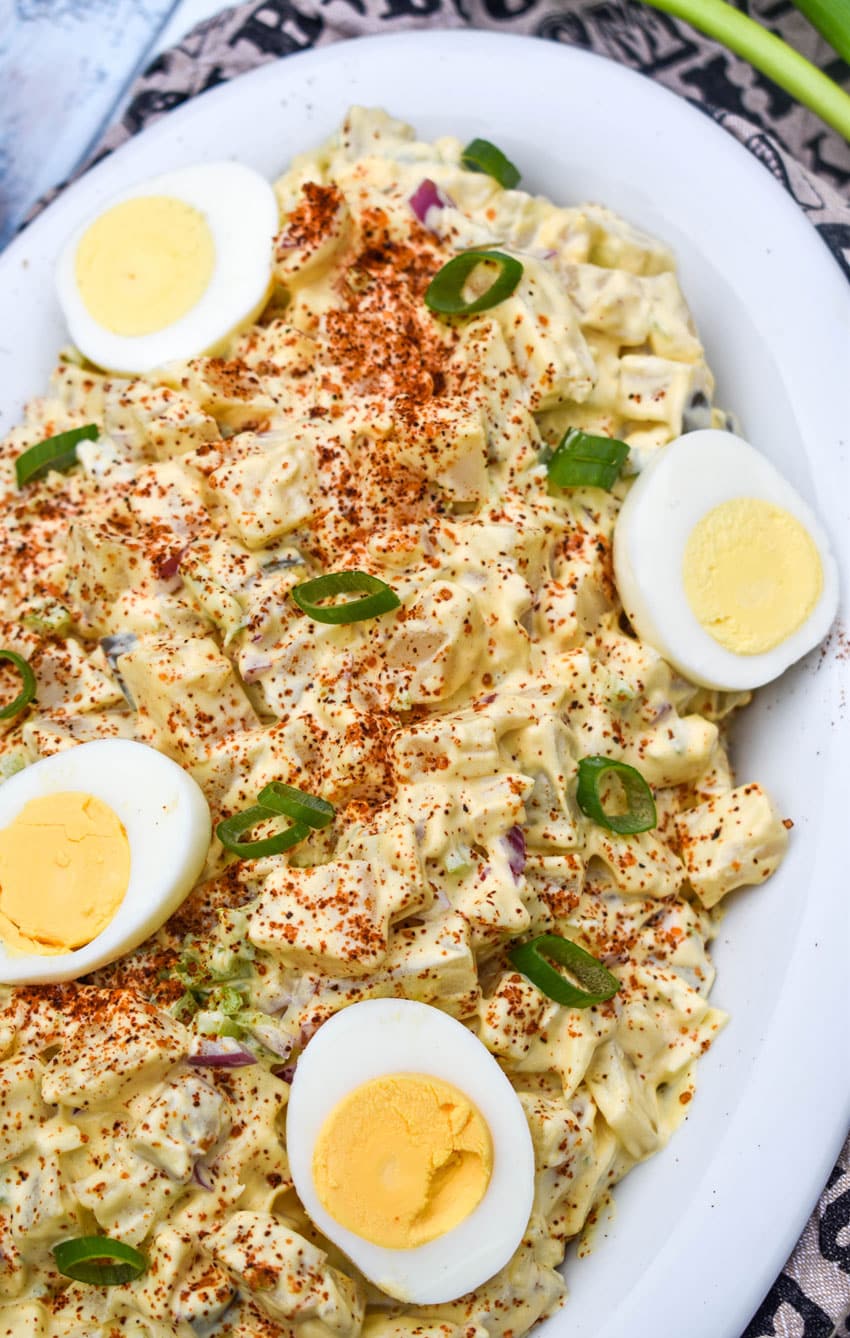 smoked potato salad topped with hard boiled egg halves in a white serving dish