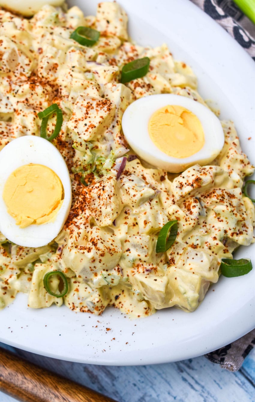 smoked potato salad topped with hard boiled egg halves in a white serving dish