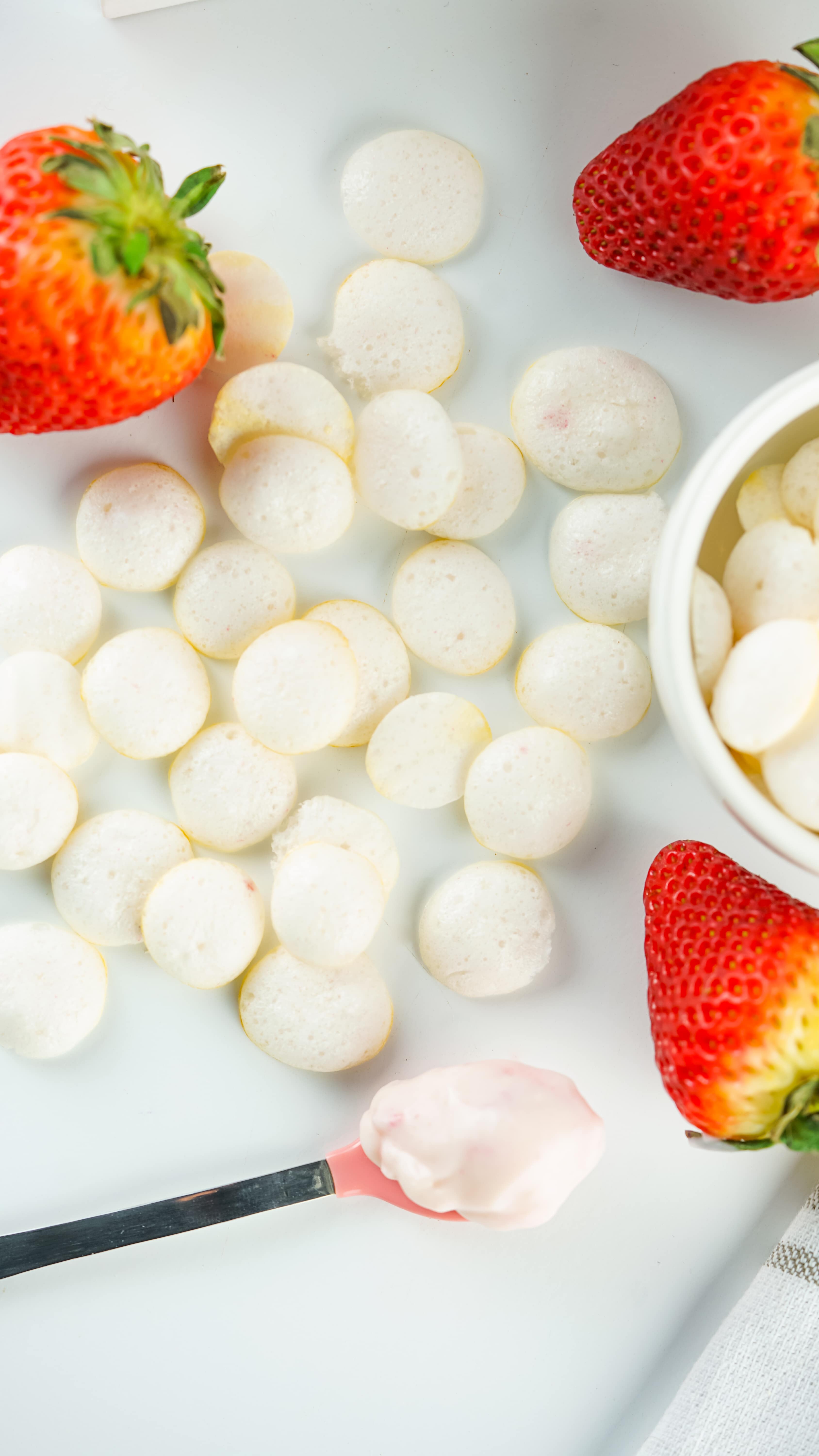 homemade yogurt melts on a wooden table with fresh strawberries in the background