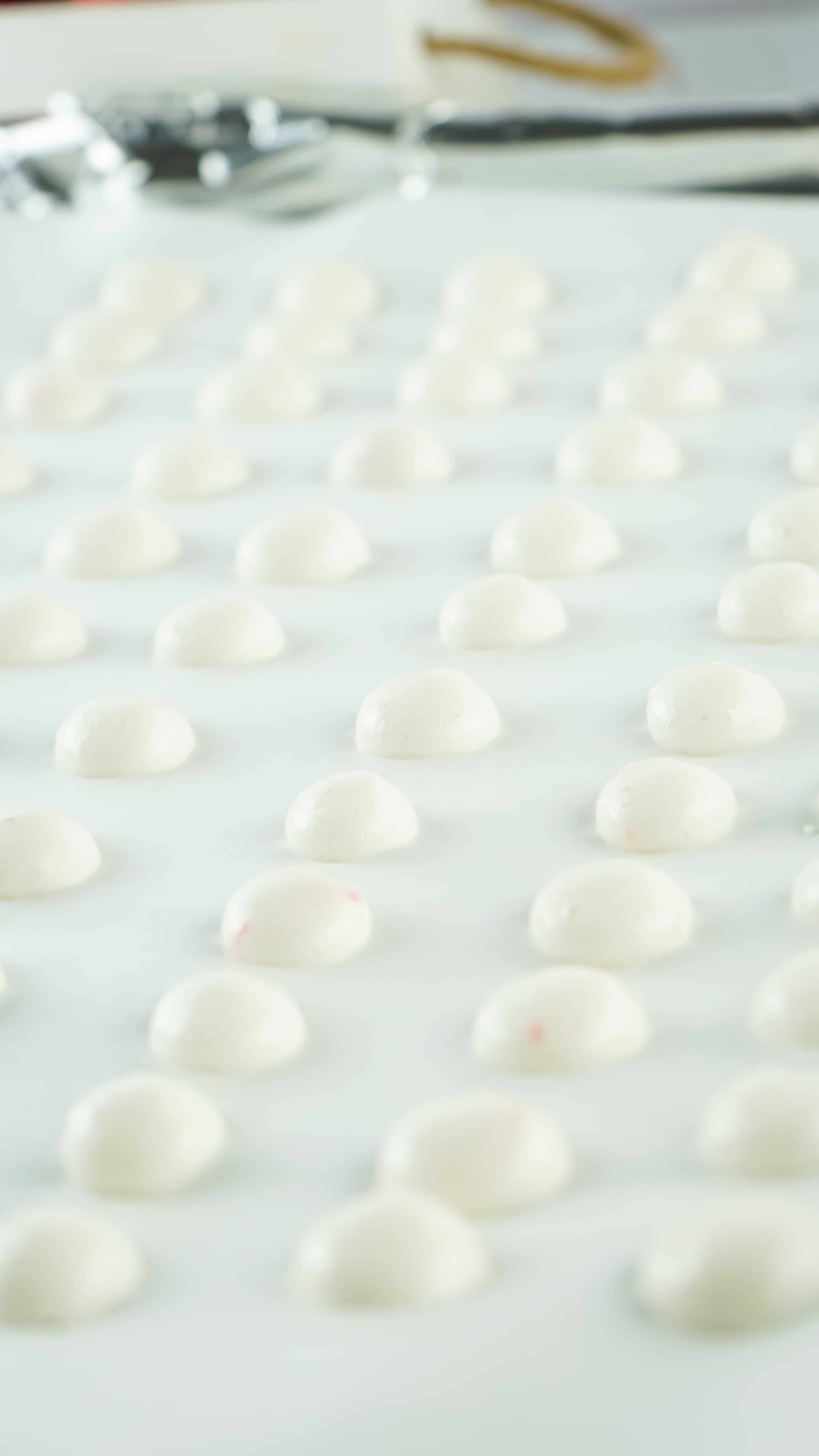 drops of strawberry yogurt arranged in rows on a parchment paper lined baking sheet