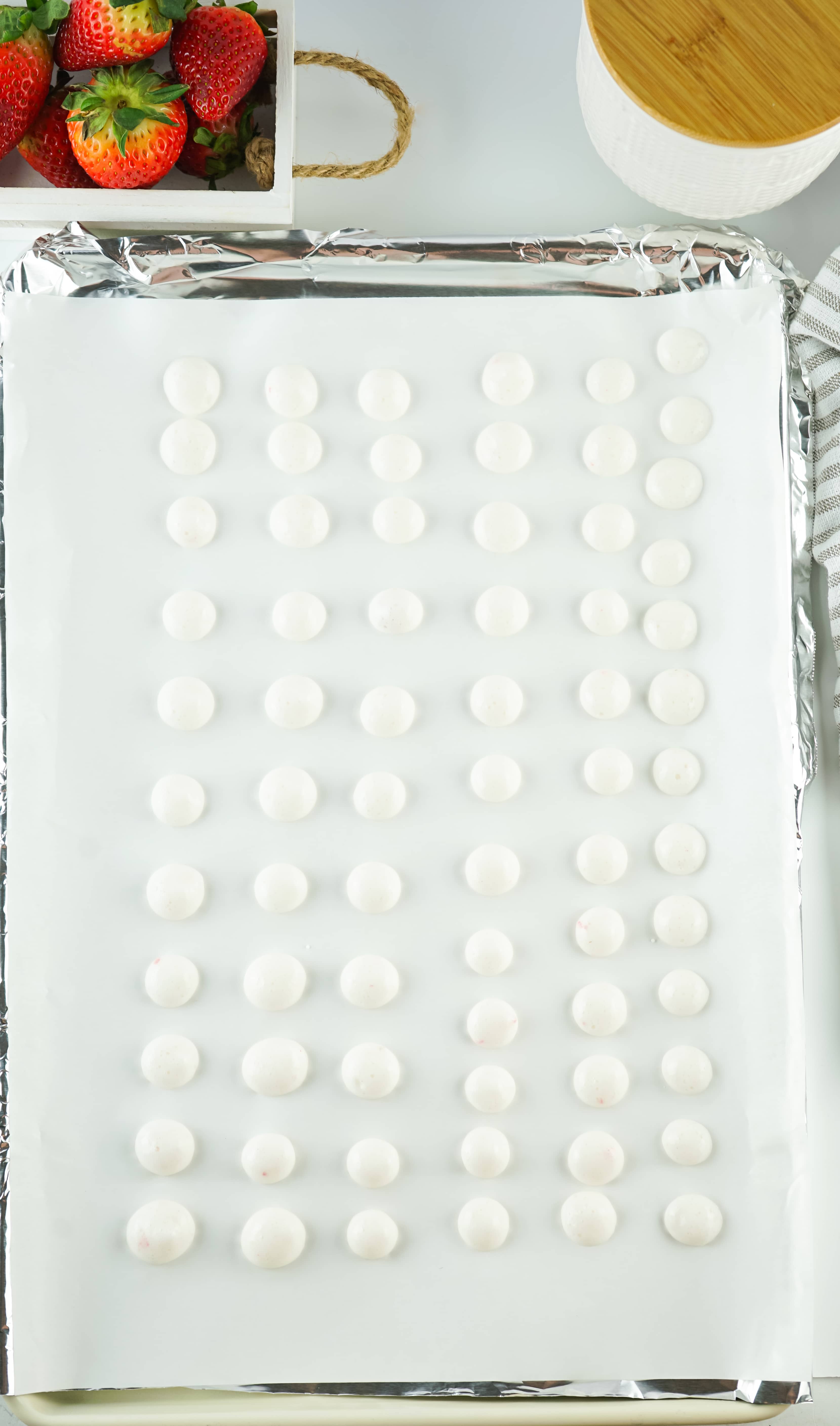 drops of strawberry yogurt arranged in rows on a parchment paper lined baking sheet