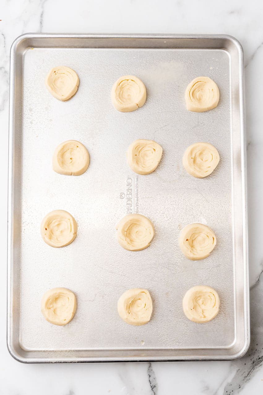 unbaked crescent roll dough pastries arranged in rows on a metal sheet pan