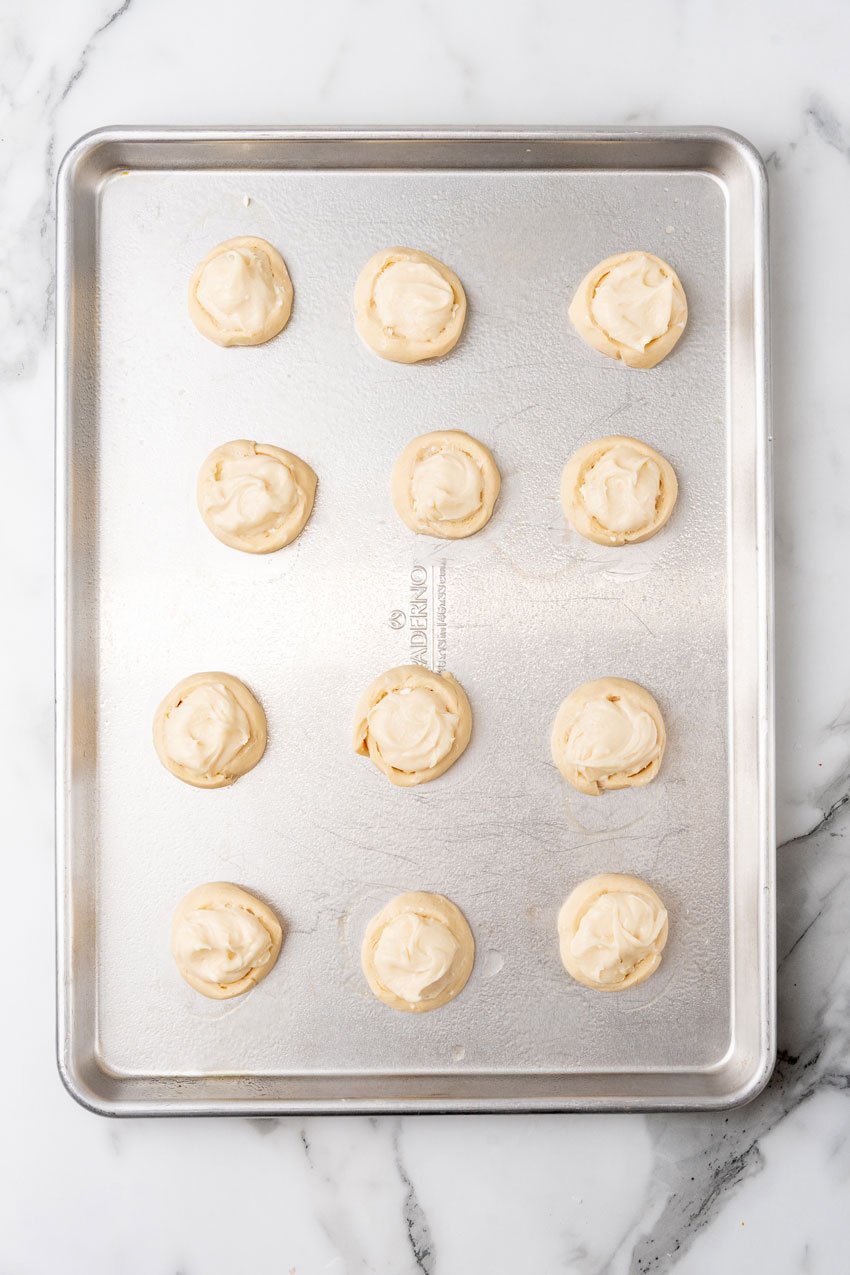 unbaked cream cheese filled pastries on a metal baking sheet