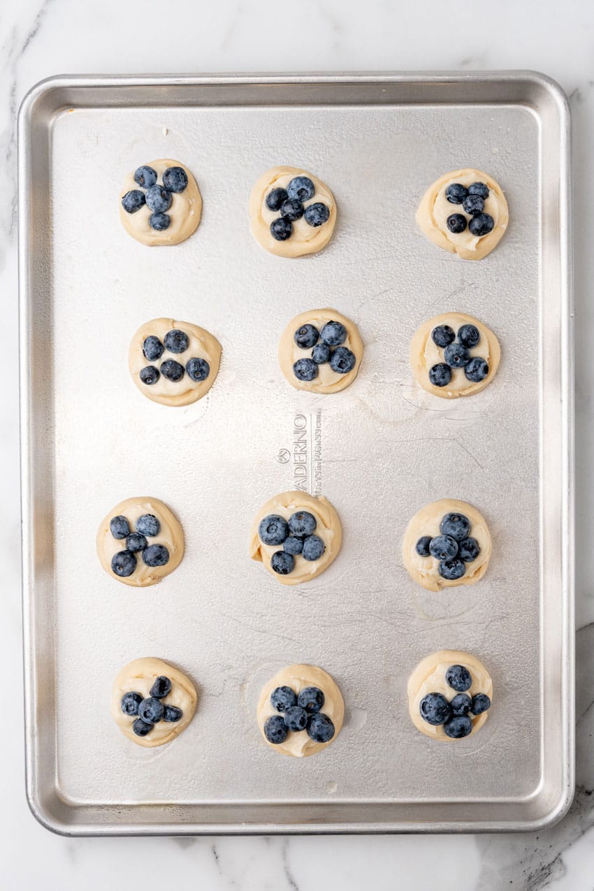 unbaked blueberry cream cheese danish arranged in rows on a metal baking sheet