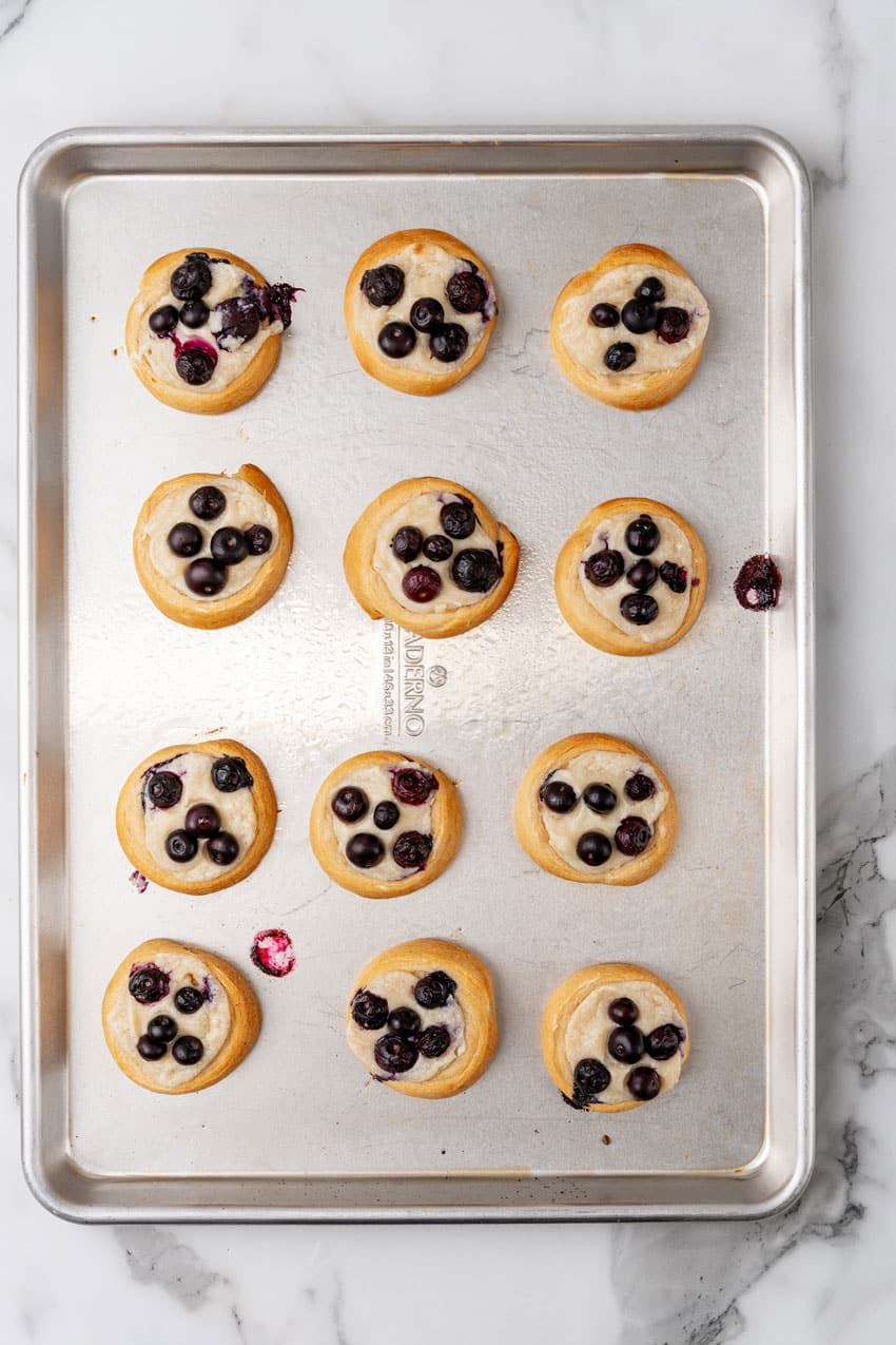 baked blueberry cream cheese danish arranged in rows on a metal baking sheet
