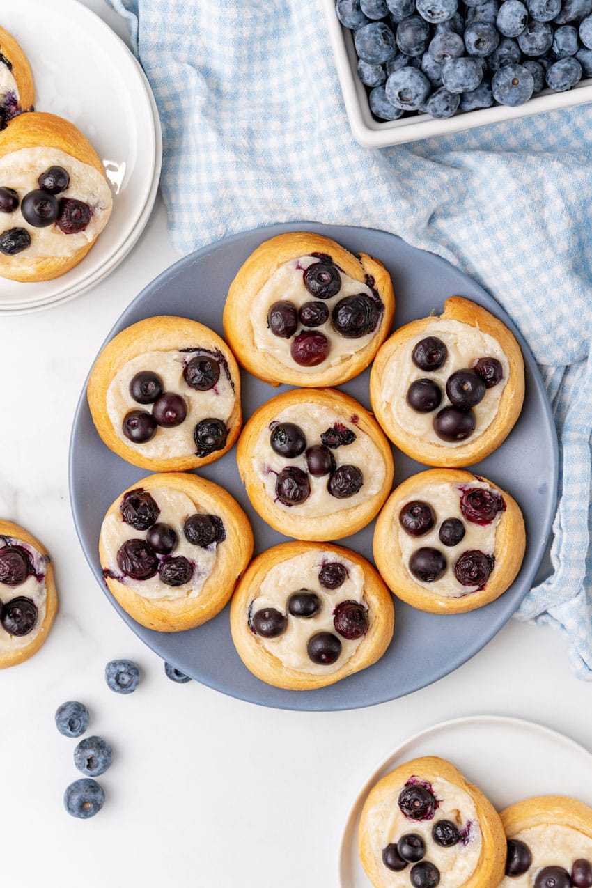 an overhead image showing blueberry cream cheese danishes arranged on a blue plate