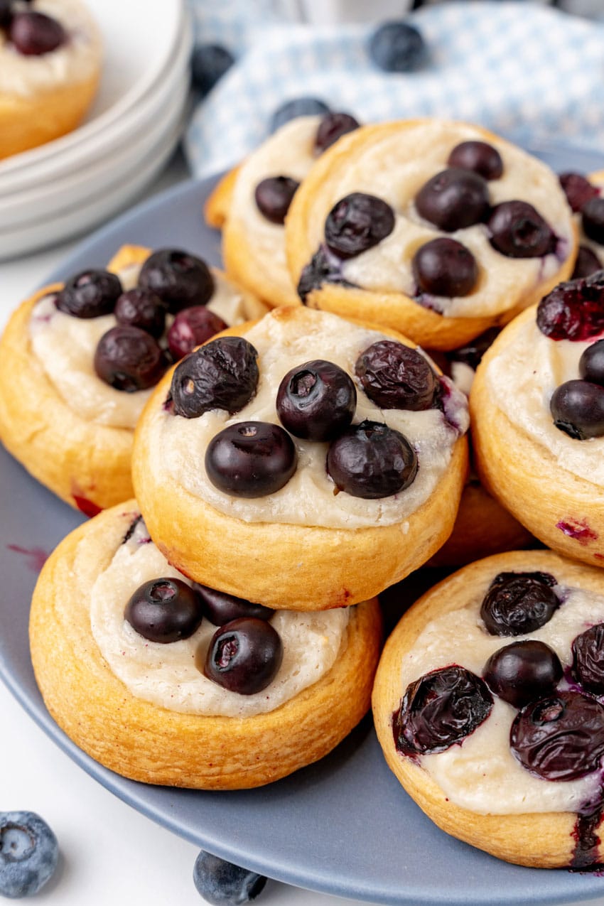 blueberry cream cheese danishes stacked on a blue plate