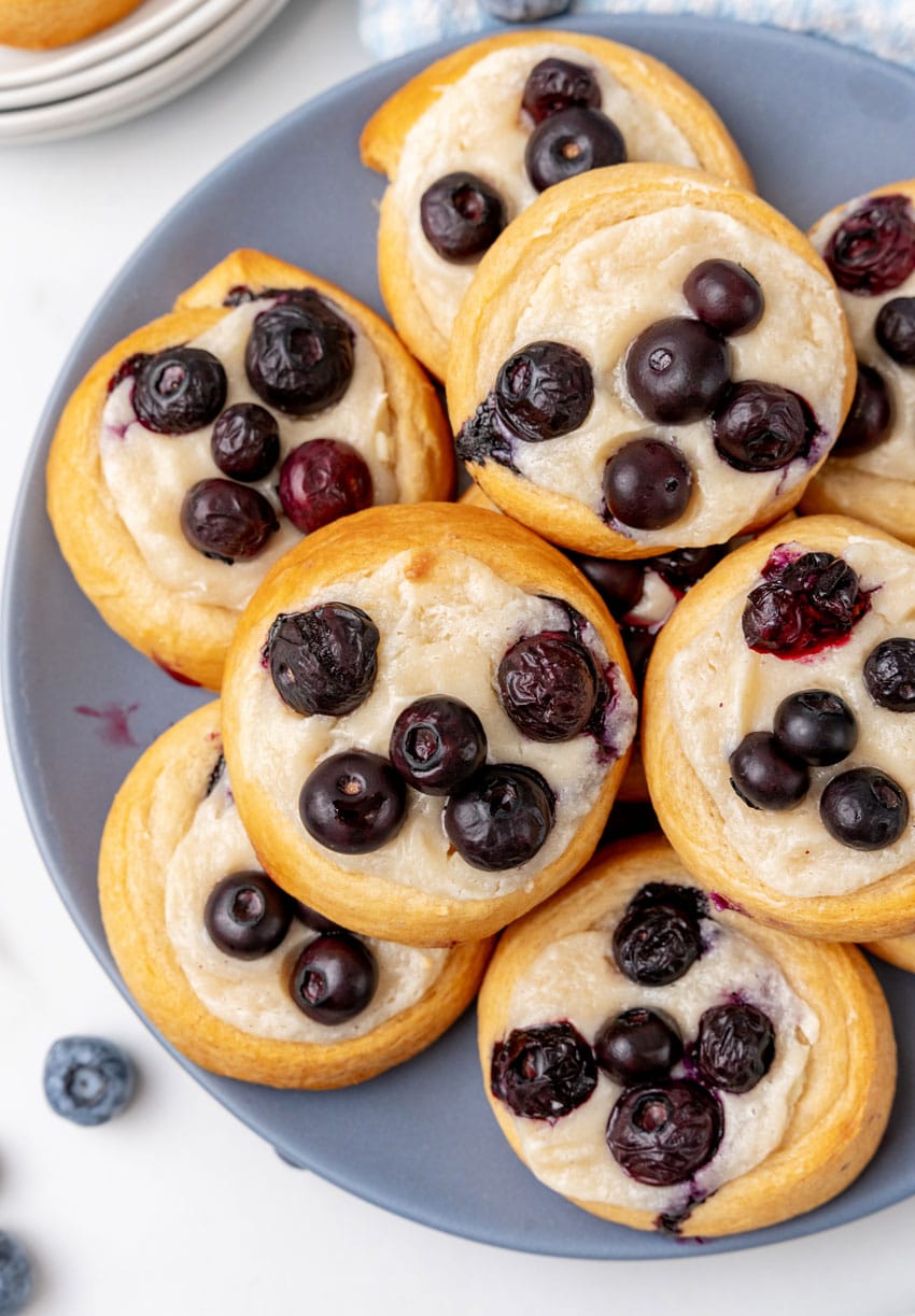blueberry cream cheese danishes stacked on a blue plate