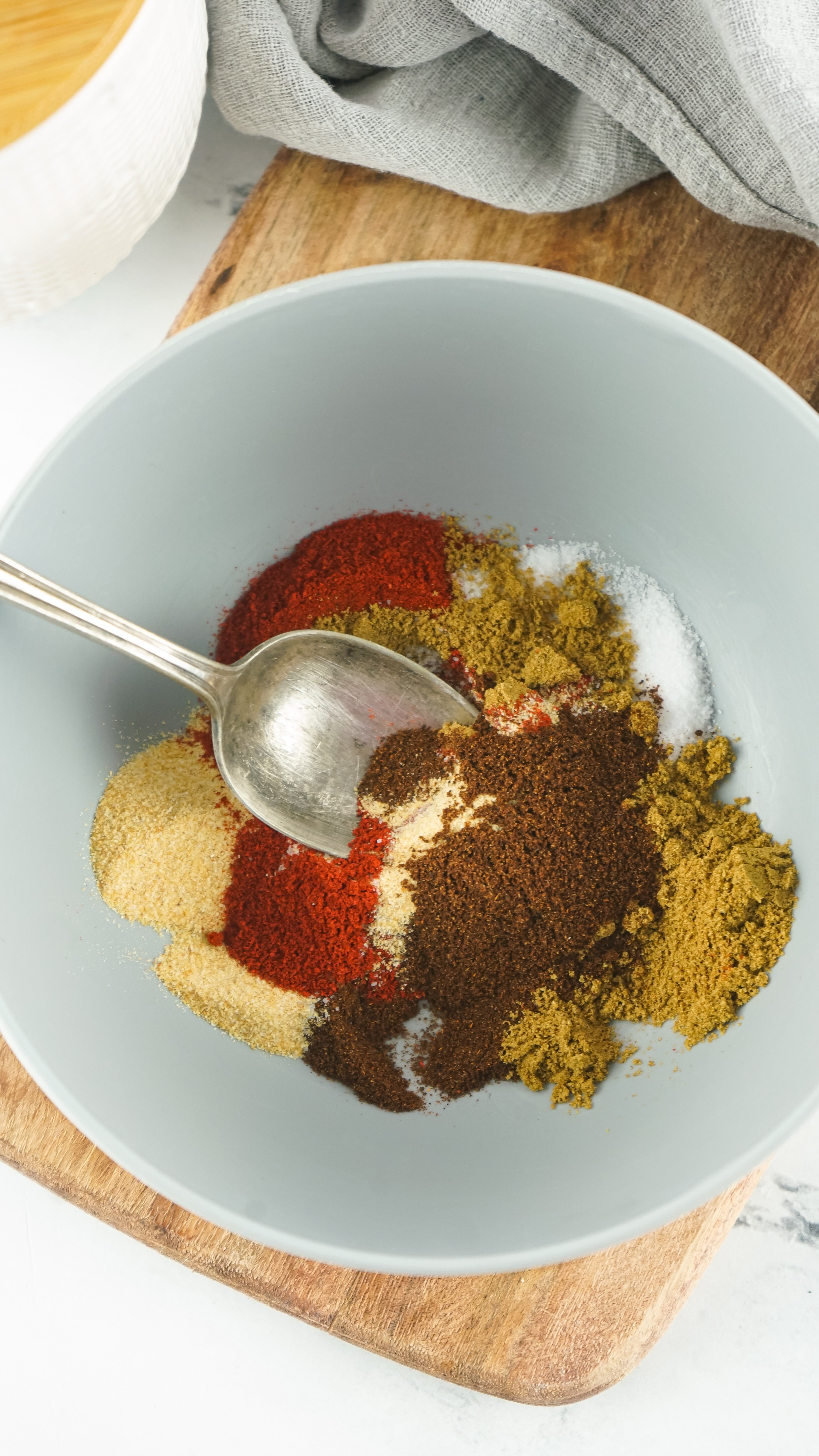 a silver spoon mixing spices together in a small mixing bowl