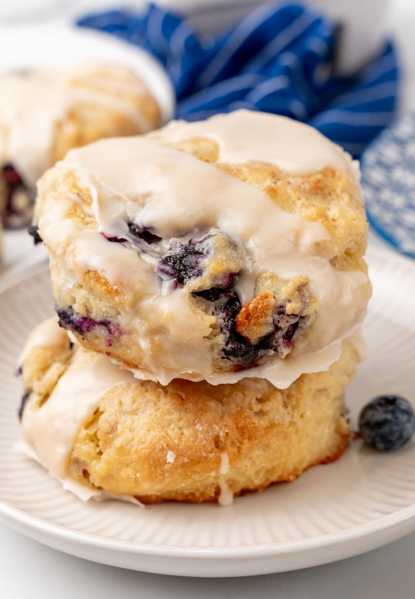 two glazed bo-berry biscuits stacked on a small white plater
