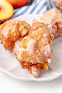 a close up of glazed peach fritters on a small white plate