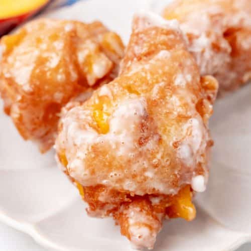 a close up of glazed peach fritters on a small white plate
