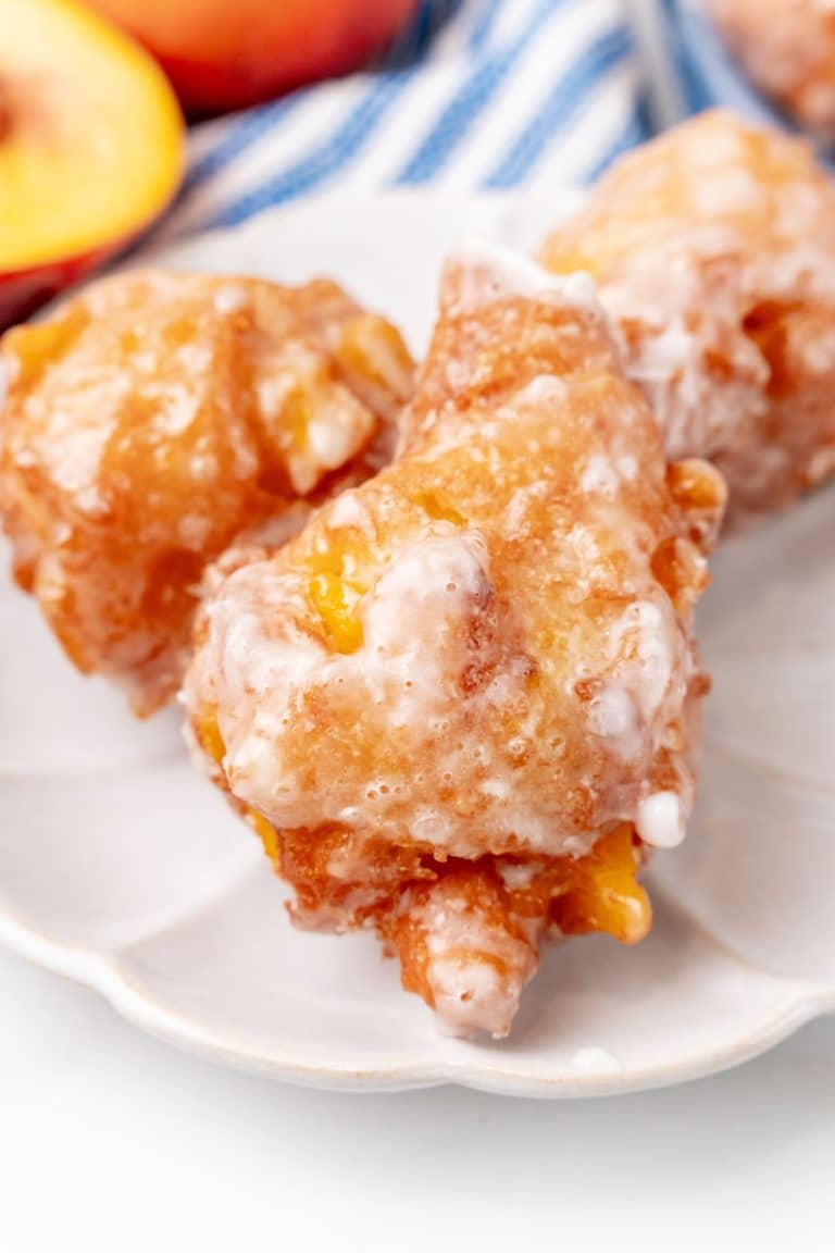 a close up of glazed peach fritters on a small white plate