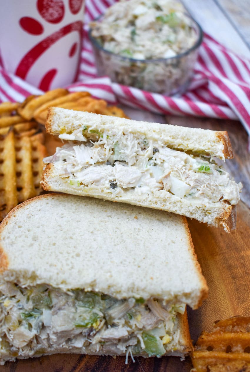 two halves of a chick fil a chicken salad recipe sandwich on a wooden cutting board
