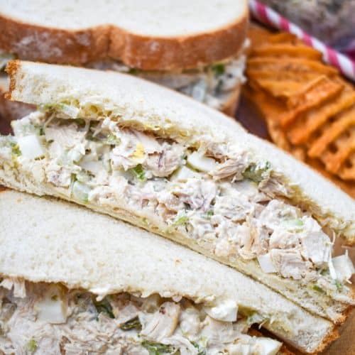 two halves of a chick fil a chicken salad recipe sandwich on a wooden cutting board