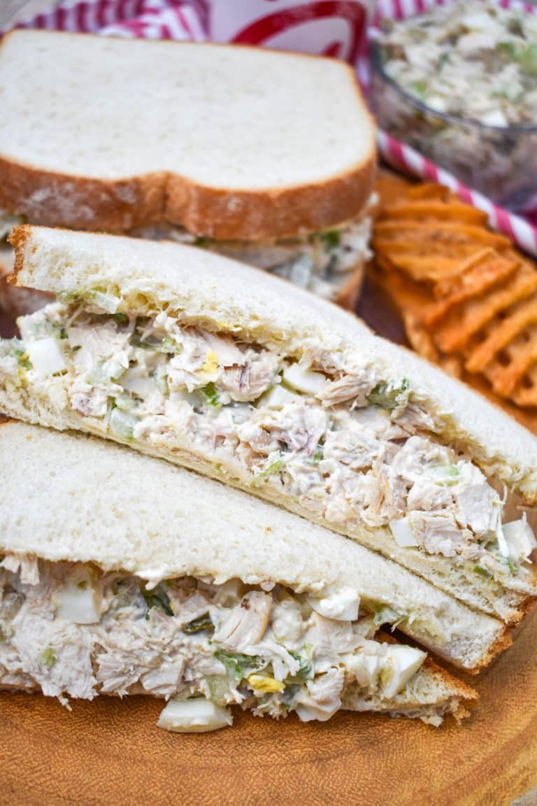 two halves of a chick fil a chicken salad recipe sandwich on a wooden cutting board