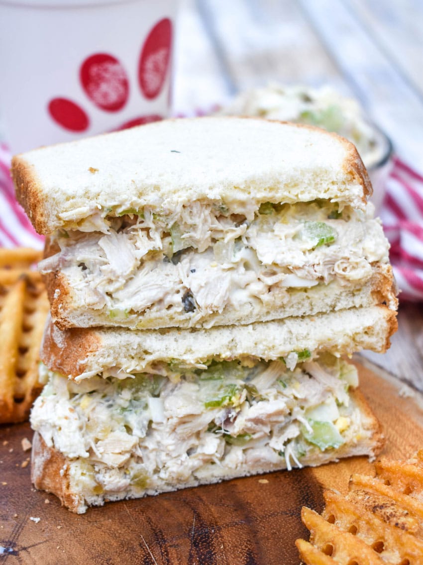 two halves of a chick fil a chicken salad recipe sandwich on a wooden cutting board