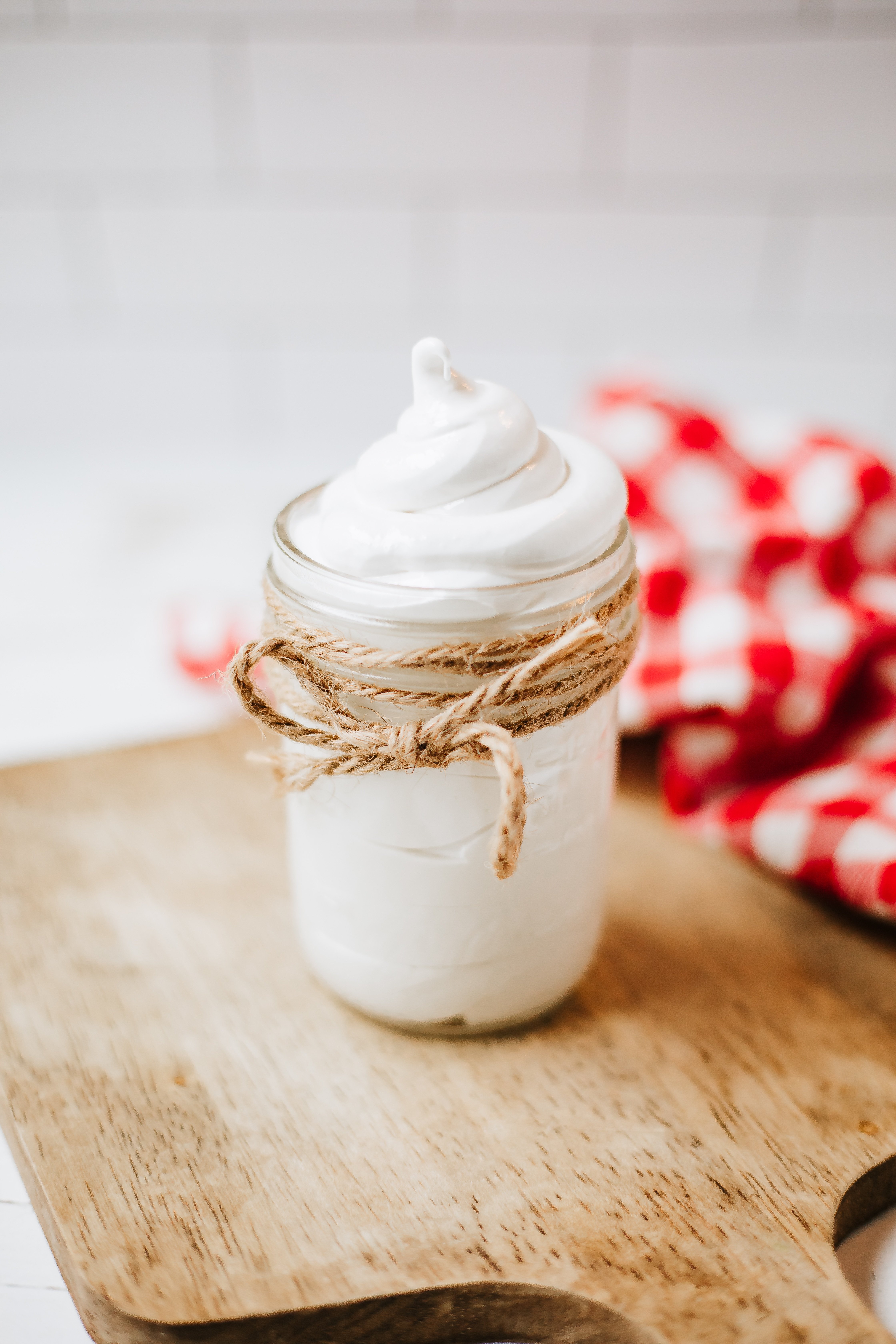 homemade marshmallow fluff in a glass jar on a wooden countertop