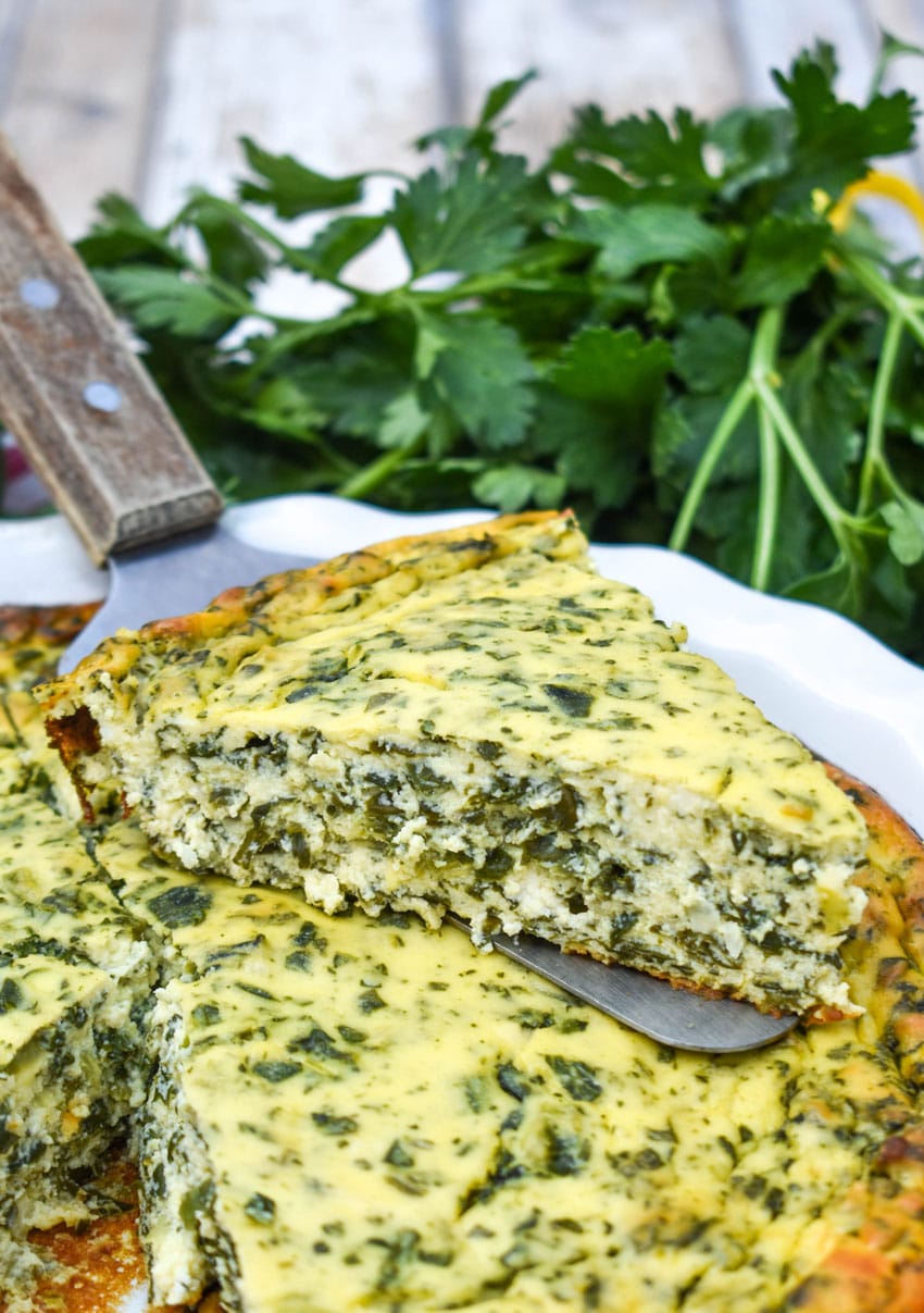 a wooden handled spatula holding up a slice of spinach ricotta pie