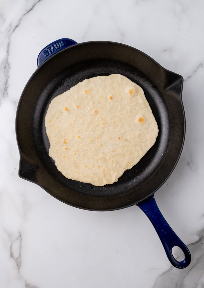 a cooked homemade flour tortilla in a black cast iron skillet