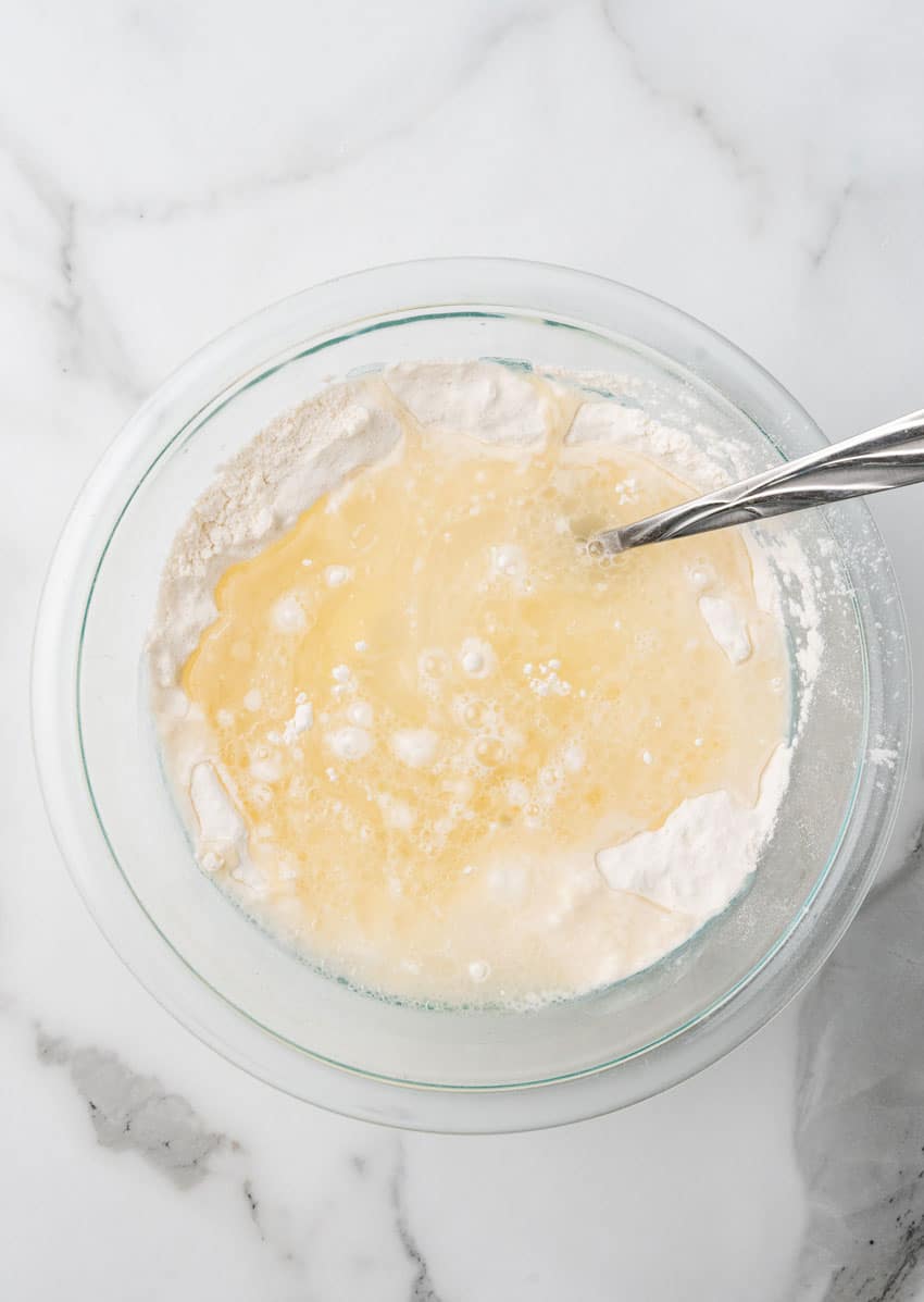 liquid on top of flour in a glass mixing bowl