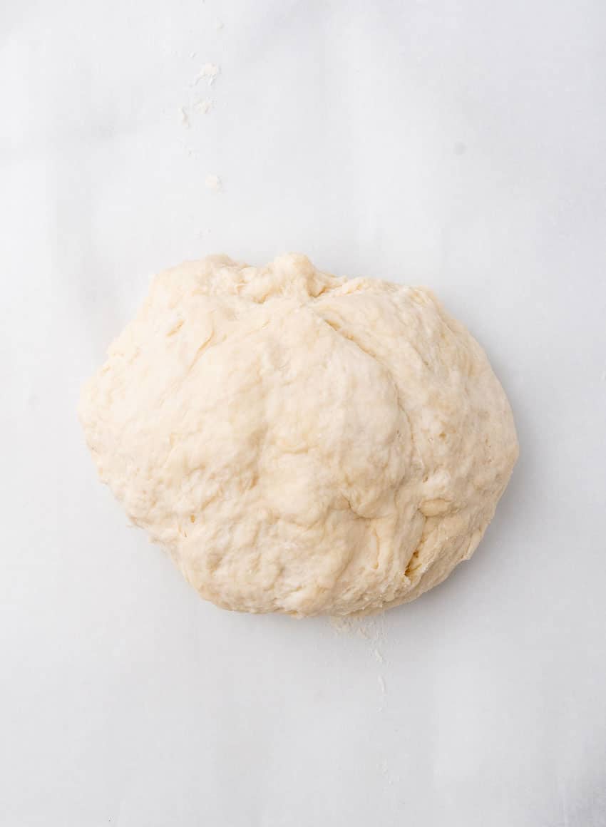 a ball of flour tortilla dough on a marble countertop