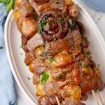 grilled steak kabobs piled on a white serving platter