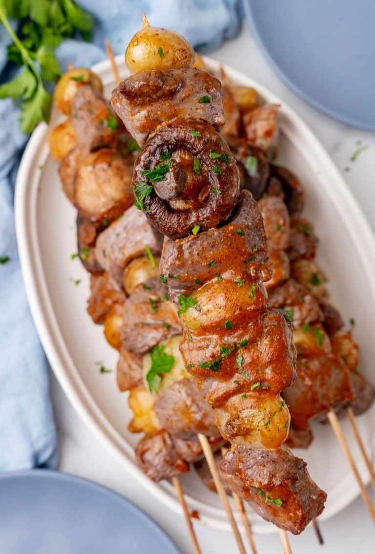 grilled steak kabobs piled on a white serving platter