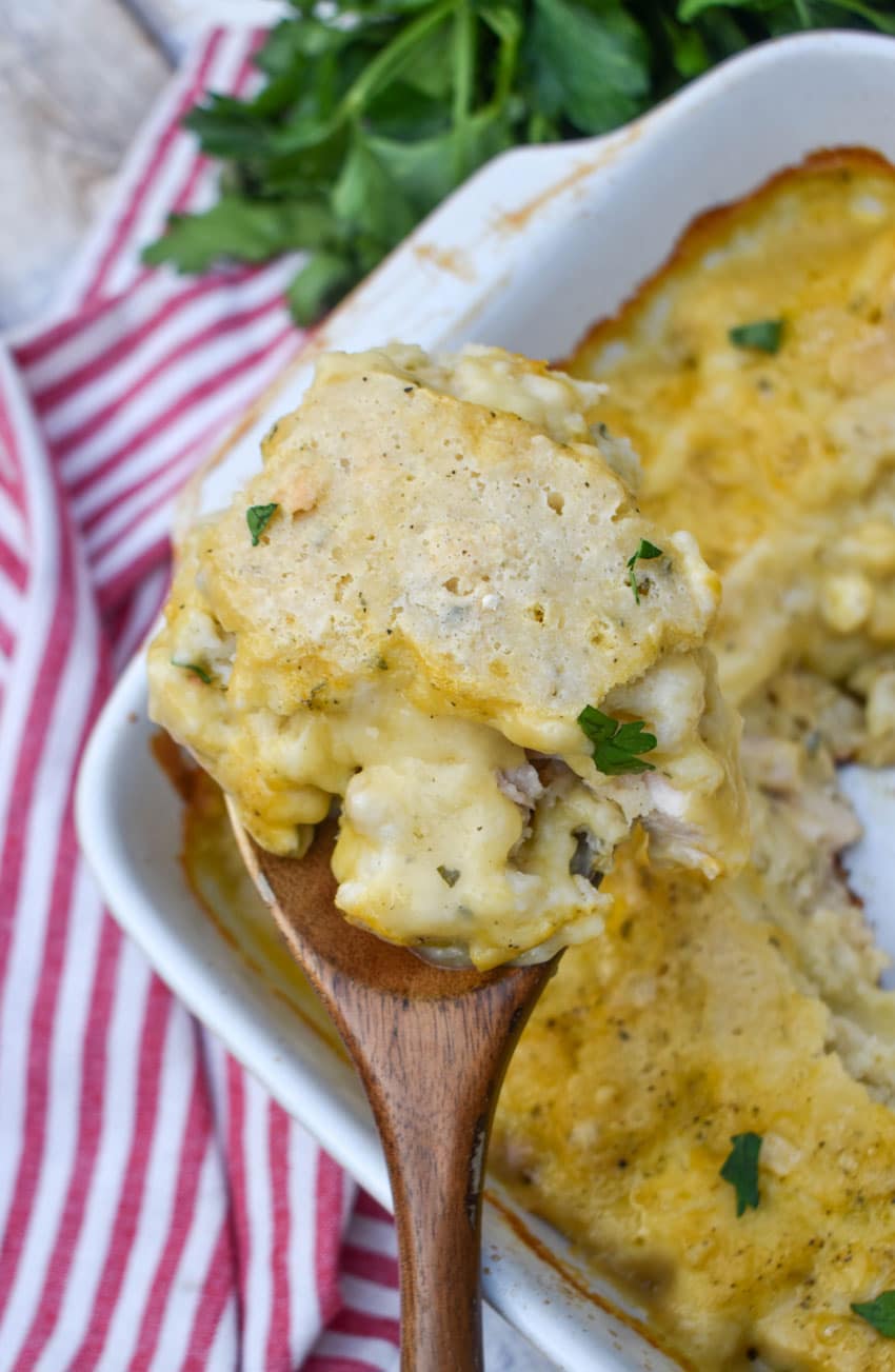 a wooden spoon holding up a scoop of chicken and dumpling casserole