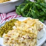 chicken and dumpling casserole next to peas on a white dinner plate