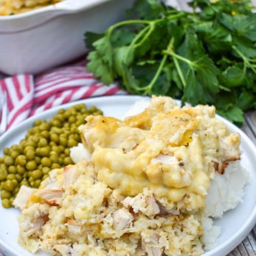 chicken and dumpling casserole next to peas on a white dinner plate