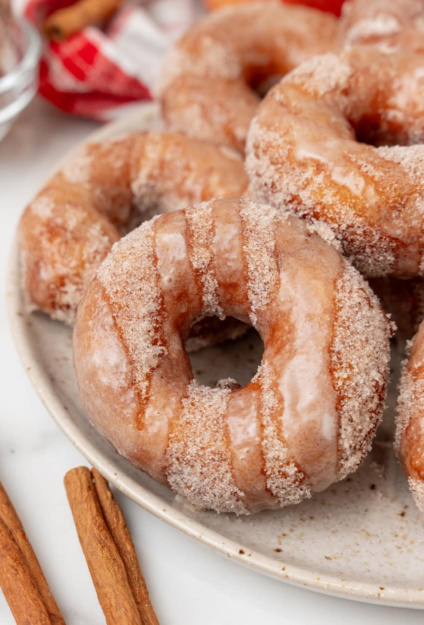 apple cider donuts stacked on a white serving plate