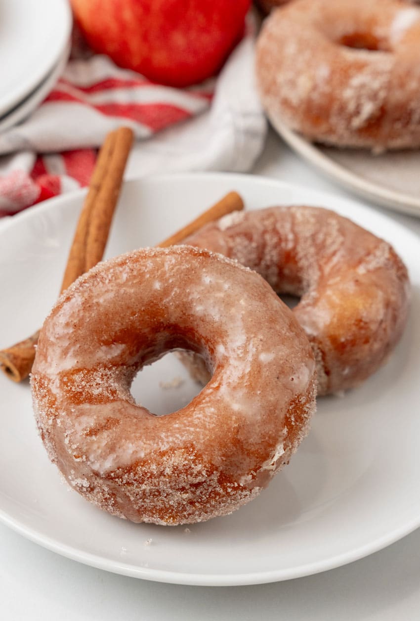 two glazed apple cider donuts on a white plate