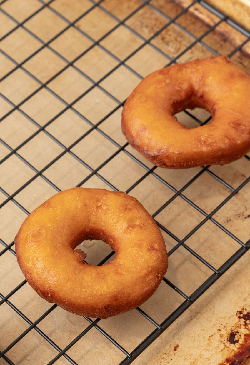 freshly fried donuts draining on a wire rack