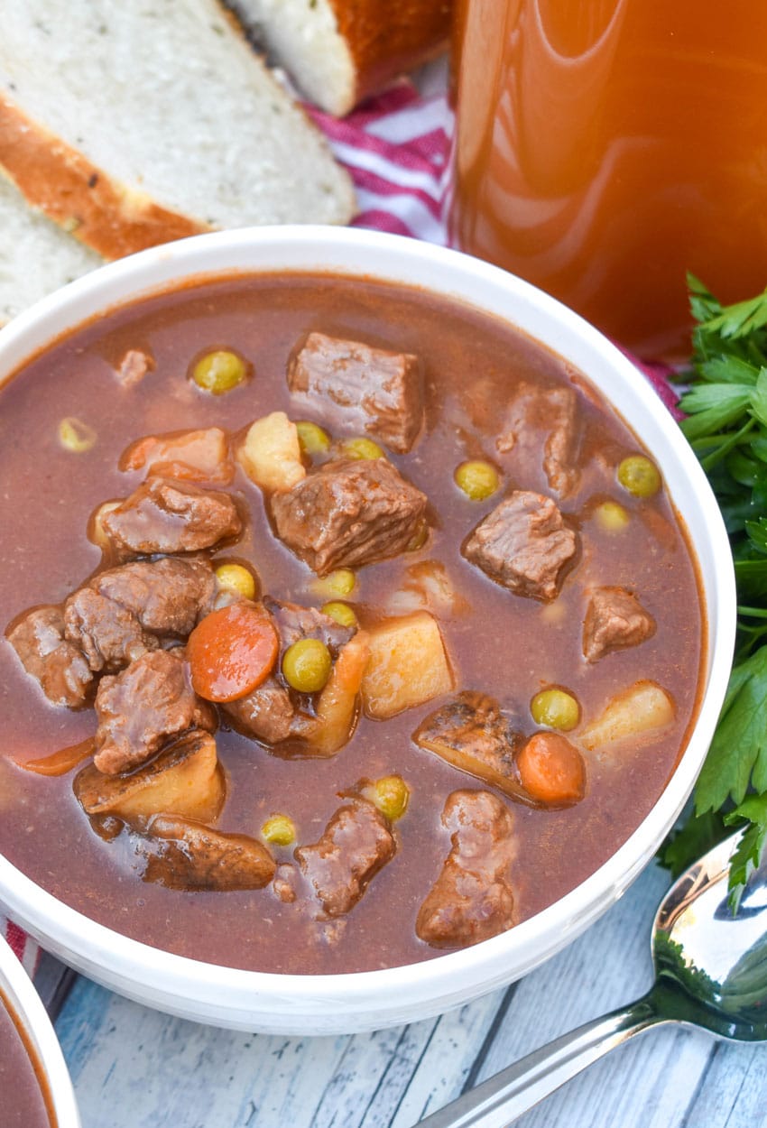 apple cider beef stew in two white bowls on a wooden table